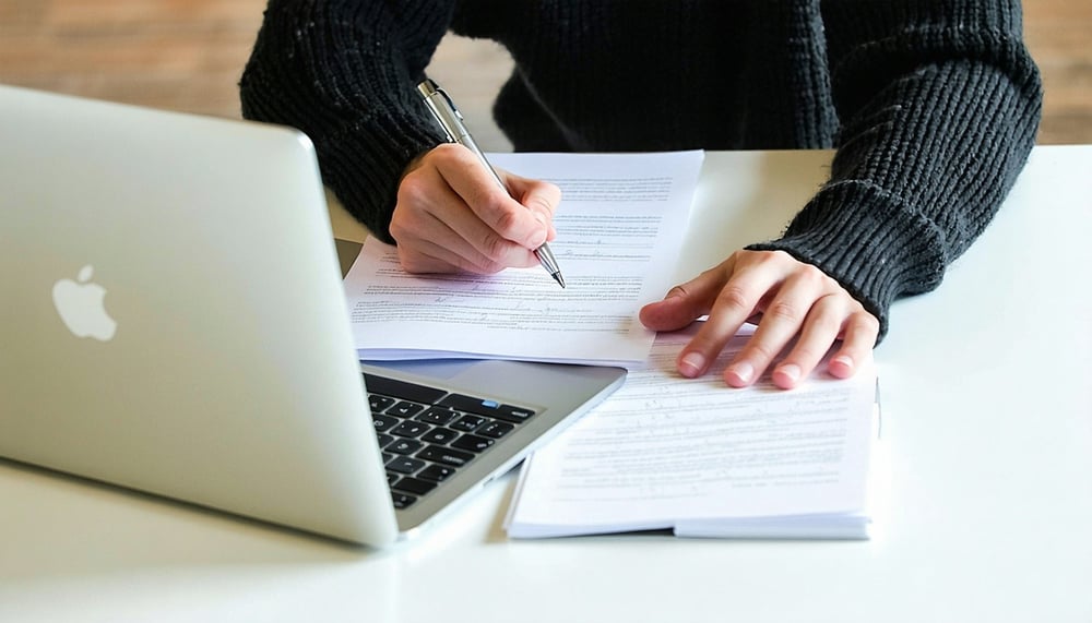 Person studying for IT certification exam with laptop and notes